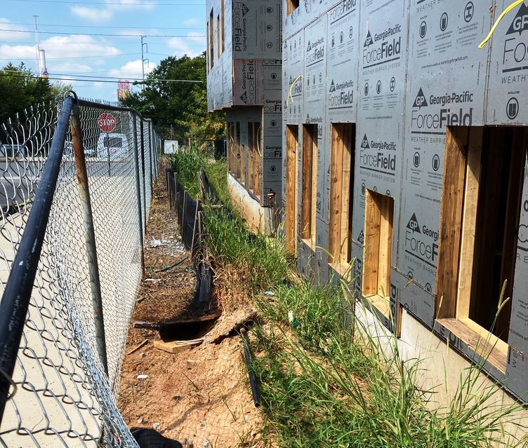 Overgrown Fence Line at commercial development site that would otherwise be covered in weeds if left untreated with herbicide to supplement routine landscape maintenance