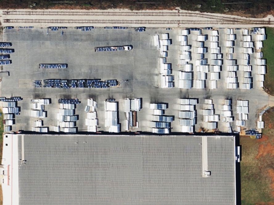 Aerial photo of a warehouse facility with rail access, heavy trailer storage, and exposed turf zones along property edges. Ideal example of a logistics or industrial site where VegClear’s targeted vegetation management improves safety, visibility, and access along fence lines, rail spurs, and concrete pads in high-traffic Southeastern distribution centers.