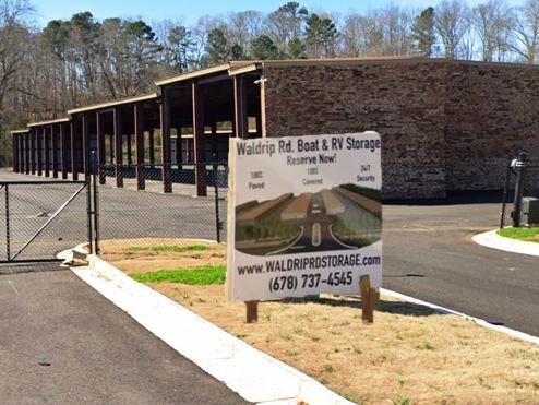 Self Storage Sign Near Cell Tower Parcel with Overgrown Kudzu and Landscape Needing Herbicide Treatment