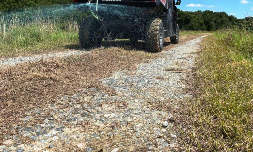 Licensed VegClear operator applying broadcast herbicides to utility road for year-round weed control, ensuring critical equipment and power generation areas are protected.