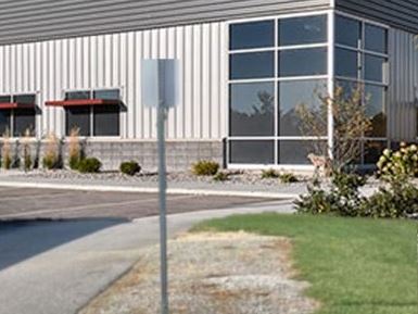 Industrial building with landscaped areas, and pavement showing weeds killed in gravel