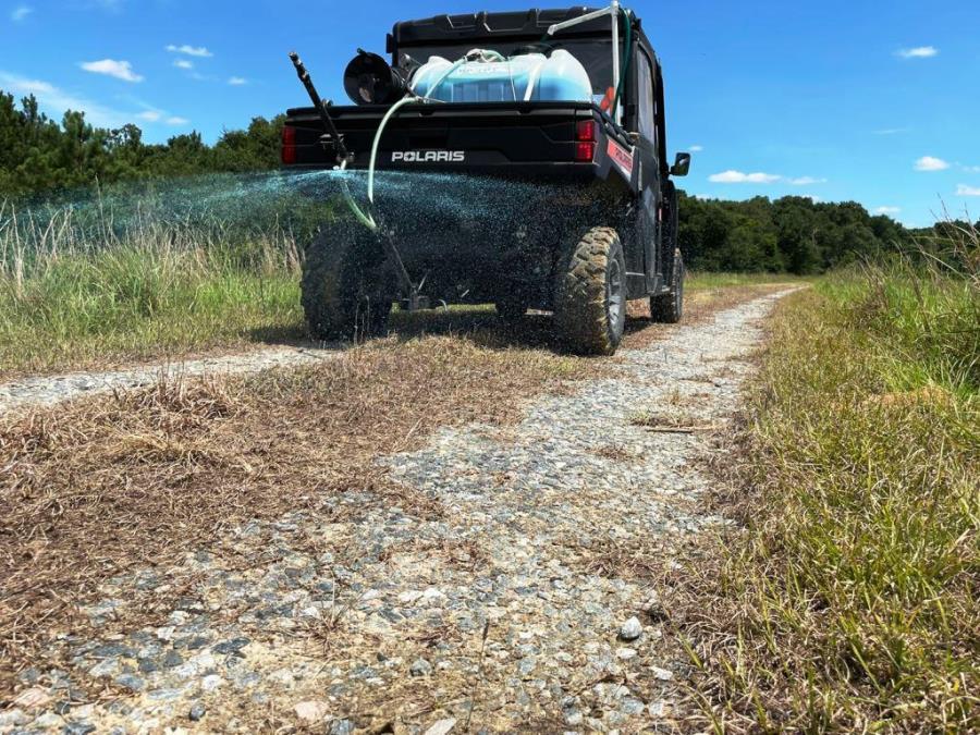 VegClear Polaris UTV operated by a licensed applicator with mounted herbicide equipment treating with vegetation control on industrial property perimeter.