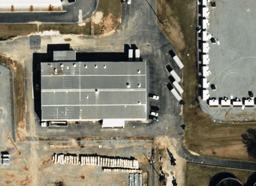 Industrial vegetation management professional spraying herbicide around a fuel or chemical storage tank to prevent weed growth, protect infrastructure, and maintain a clean, compliant bare ground site.