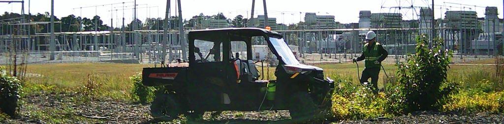 VegClear technician using ATV-mounted spray equipment applies selective herbicide near a power substation to control vegetation growth and maintain safe, compliant utility infrastructure access.