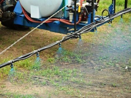 VegClear applying granular herbicides forming an invisible barrier over soil where seeds would otherwise germinate preventing weeds on this commercial property