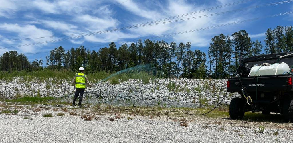 Licensed applicator performing roadside and right-of-way weed control with UTV spray equipment along a utility and drainage corridor. Herbicide application for municipal roads, access routes, and infrastructure maintenance.