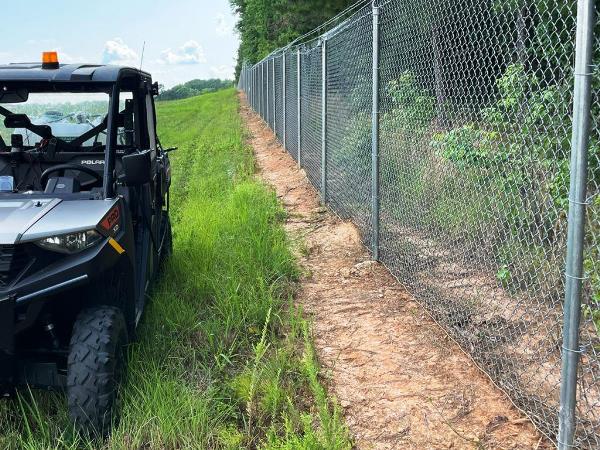 fence line treated for total vegetation control through proactive spraying to prevent weeds in industrial settings