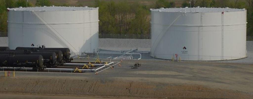 Large industrial fuel storage tanks with connected rail terminal. Image shows clean gravel and minimal vegetation due to effective weed control measures.
