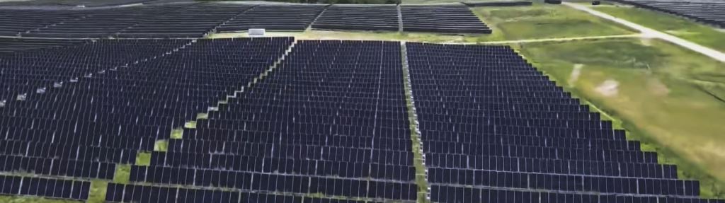 Expansive Solar Farm gravel lot with invasive weeds controlled by herbicide applications With Panels Surrounded by Well-Maintained Vegetation
