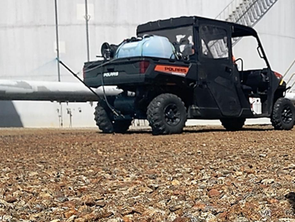 Polaris UTV equipped with a mounted herbicide sprayer treating a gravel lot at an industrial tank farm. Example of VegClear’s industrial weed control and vegetation management services for secure facilities.