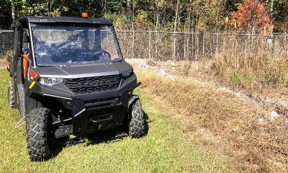 Utility terrain vehicle staged for fence line vegetation control along an industrial site perimeter, supporting selective woody and broadleaf management for long term industrial vegetation management across Georgia and the Southeast.
