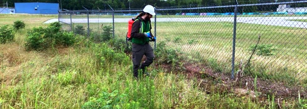 Licensed technicians applying herbicide at an energy facility to control weeds and invasive plants along perimeter security fence line. VegClear provides licensed herbicide applications for industrial vegetation management, ensuring compliance and safety across pipelines, utilities, and facilities.