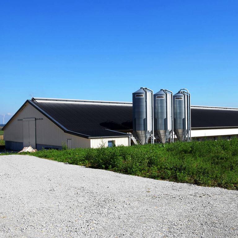 Poultry house with metal roof, service access lanes, and gravel drive, showing typical farm sites treated by VegClear for weed and grass control along fencelines, gravel lots, and driveways to maintain clean, compliant poultry house operations.