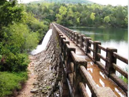 Bridge built into dam with a clear spillway free of intrusive vegetation, demonstrating the role of vegetation management in maintaining operational readiness and water flow efficiency