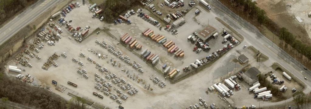 An industrial outdoor storage yard with steady truck and heavy equipment traffic, featuring well-maintained gravel and asphalt surfaces. Weed control spray application prevents vegetation overgrowth, ensuring clear access for operators and reducing maintenance costs. Professional vegetation management services for industrial storage sites in Georgia and South Carolina.