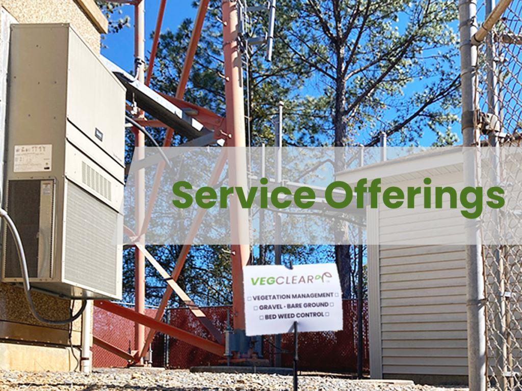 Cell tower compound with VegClear sign highlighting weed control service offerings such as bare ground spraying, gravel lot vegetation management, fence line weed control, and pre-emergent programs.