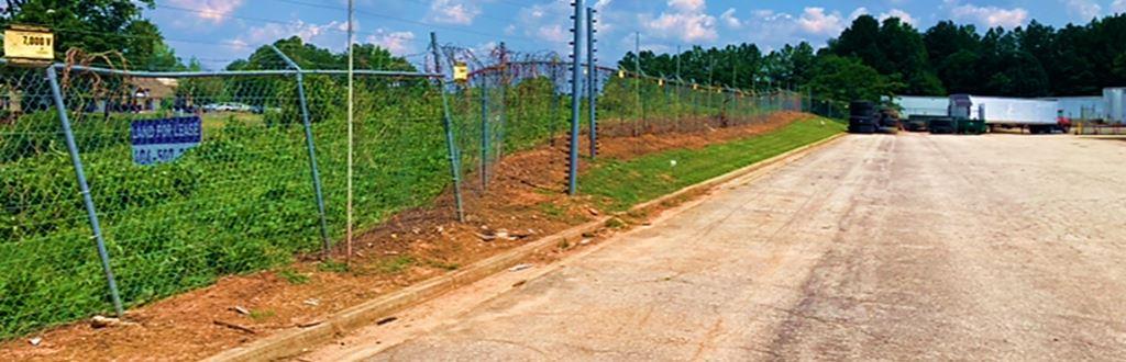 Perimeter fence line at an industrial site in Ellenwood, GA showing cleared and treated ground after VegClear’s vegetation management service. The contrast between previously overgrown sections and newly maintained areas demonstrates effective brush and vine control. This treatment improves visibility, strengthens fence security, and reduces the long-term maintenance burden for industrial operators like Snider Fleet Solutions.
