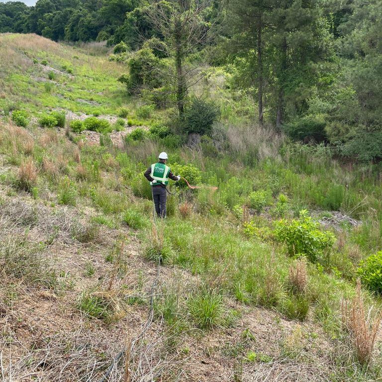 Licensed herbicide applicator performs selective vegetation management on an industrial hillside to improve access, visibility, and long-term site maintenance.