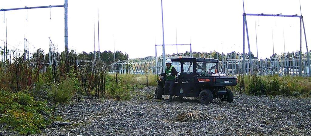VegClear technician conducts herbicide application around a utility substation using an ATV-mounted sprayer to manage vegetation, maintain safe access, and ensure electrical infrastructure compliance.