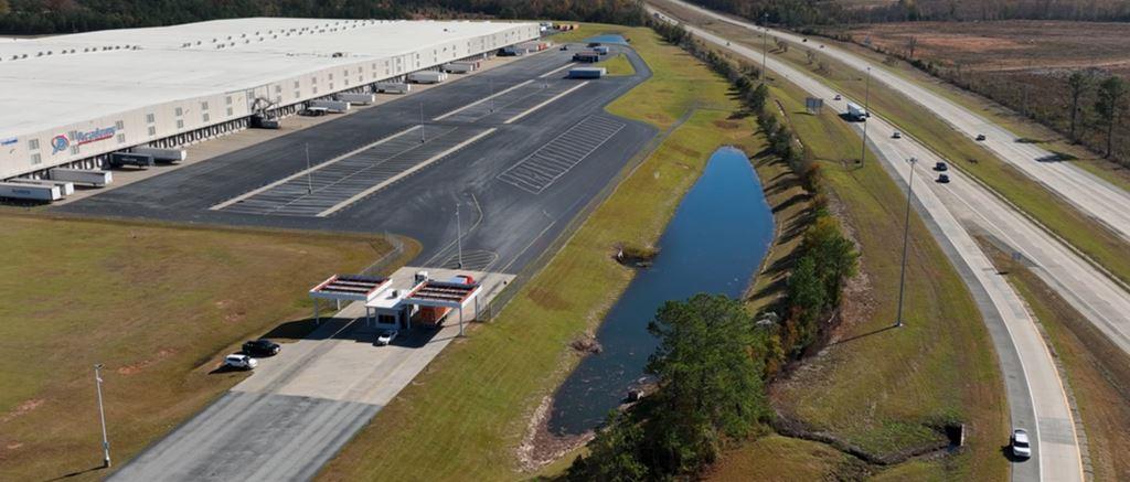 Industrial vegetation control client site showing industrial property with large distribution center cross docking facility, warehouse buildings, and guarded perimeters requiring herbicide weed management in Georgia.