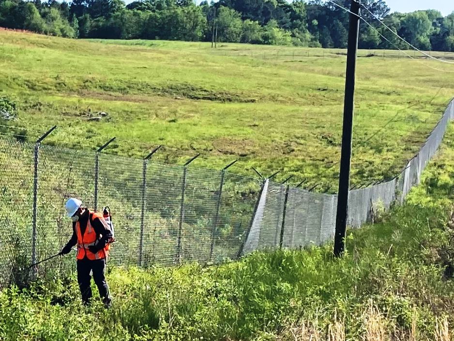 Treating minimal specified clearance along the sides of airport security fence when applying weed control.