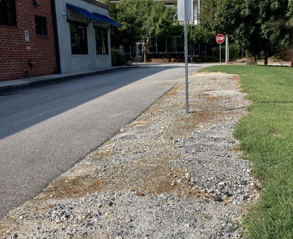 Vegetation-free gravel strip along a commercial roadside after VegClear herbicide treatment. This bare-ground weed control application prevents regrowth near signage and pavement, ensuring clean, compliant, and low-maintenance areas for municipal and industrial property managers in Georgia.