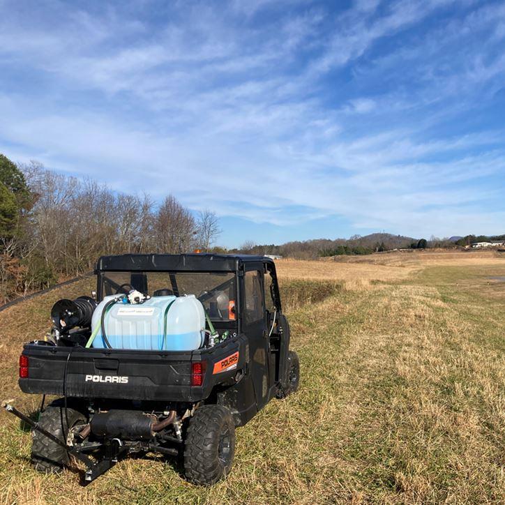UTV mounted herbicide sprayer positioned in open right of way corridor for utility vegetation management and broadcast application